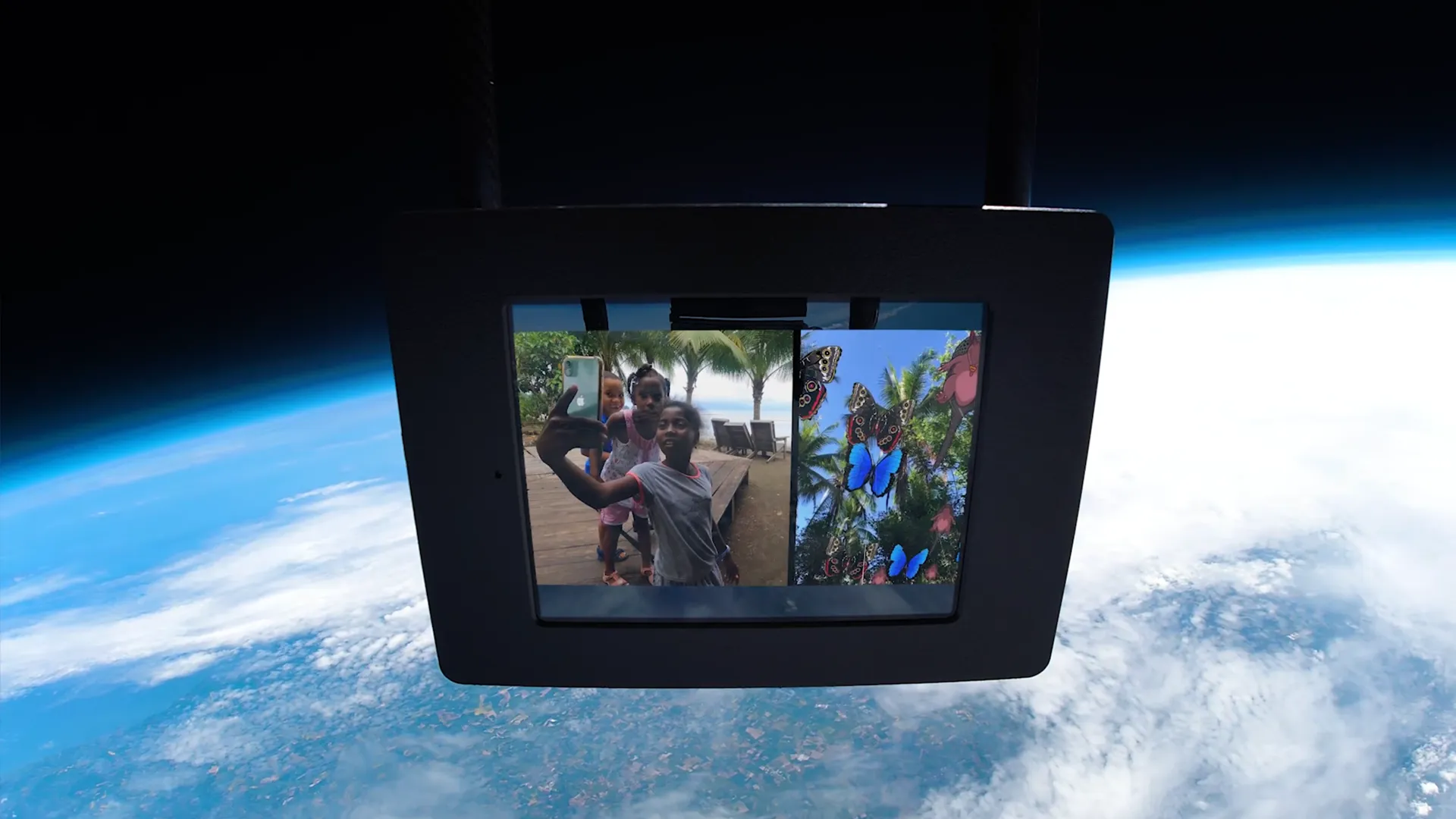 Zero Gravity - screen suspended at the edge of space above Earth, playing footage of Arusí children beside their AR butterflies and plants artwork